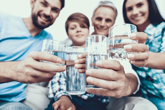 Smiling Family Drinking Water in Glasses at Home.